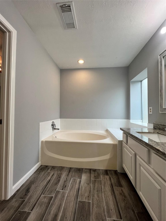 full bathroom featuring visible vents, a garden tub, vanity, and wood finished floors