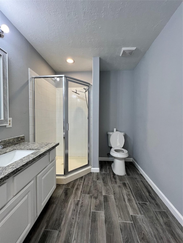 bathroom with toilet, a stall shower, visible vents, and wood finish floors