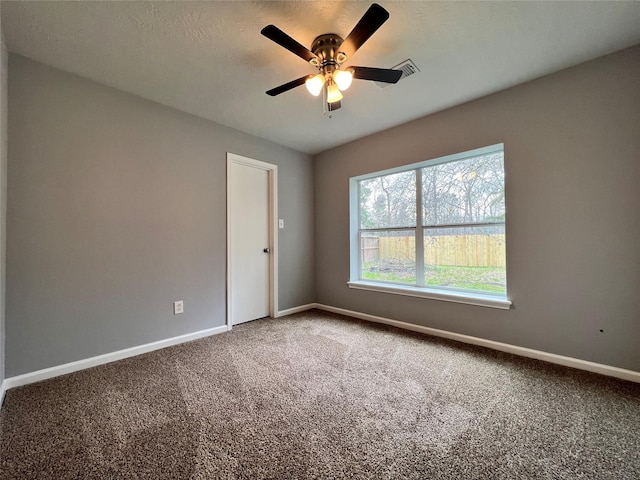 carpeted spare room featuring visible vents, ceiling fan, a textured ceiling, and baseboards