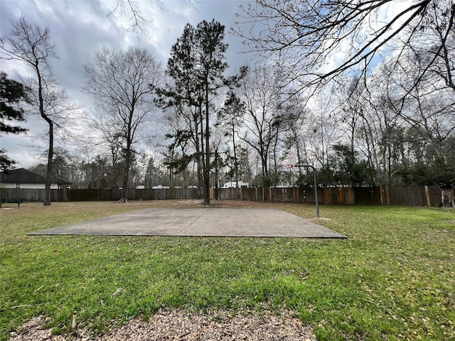 view of home's community featuring a fenced backyard, a yard, and basketball hoop