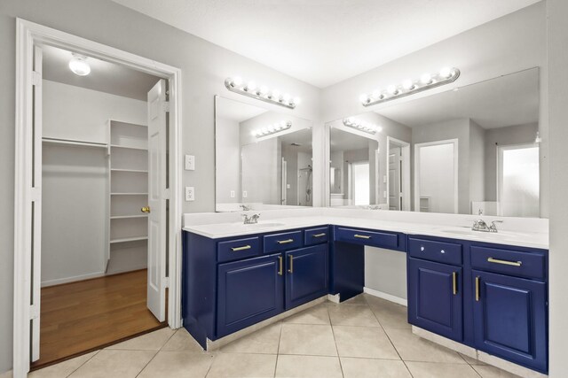 full bath with a sink, a walk in closet, double vanity, and tile patterned flooring