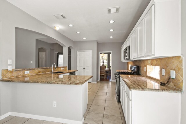 kitchen featuring visible vents, light stone counters, appliances with stainless steel finishes, white cabinetry, and a sink