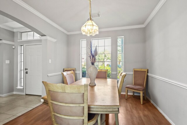 dining space featuring a notable chandelier, visible vents, wood finished floors, and ornamental molding