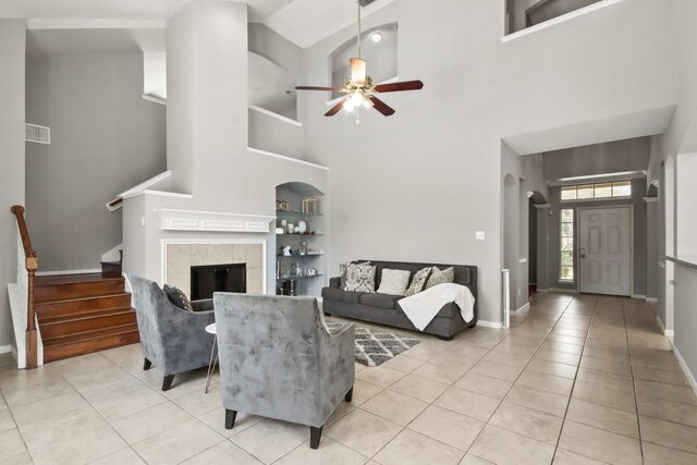 living room featuring stairway, light tile patterned floors, a tile fireplace, and built in features