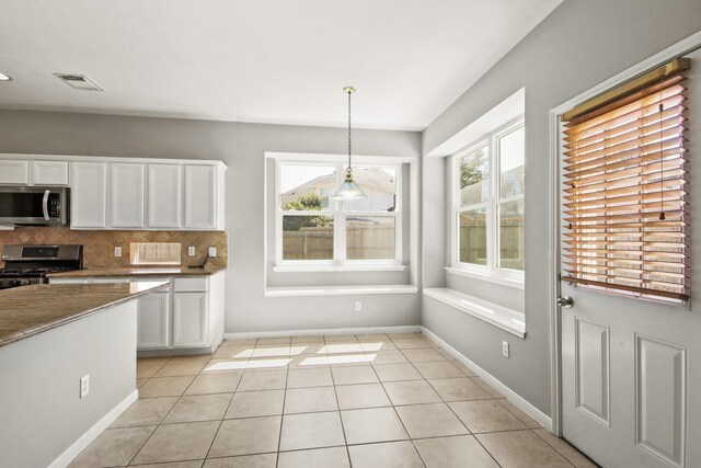 kitchen featuring visible vents, appliances with stainless steel finishes, light tile patterned flooring, white cabinets, and decorative backsplash