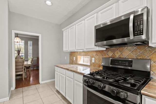 kitchen with decorative backsplash, light tile patterned flooring, white cabinetry, and stainless steel appliances