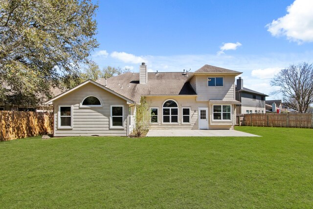 rear view of house with a patio, a yard, fence, and a chimney