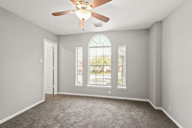 carpeted spare room with visible vents, a ceiling fan, and baseboards