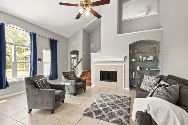 living area with a tiled fireplace, built in features, tile patterned flooring, and arched walkways