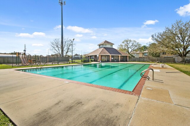 community pool with a patio area and fence