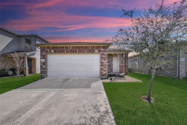 view of front of property with a garage, concrete driveway, brick siding, and a yard