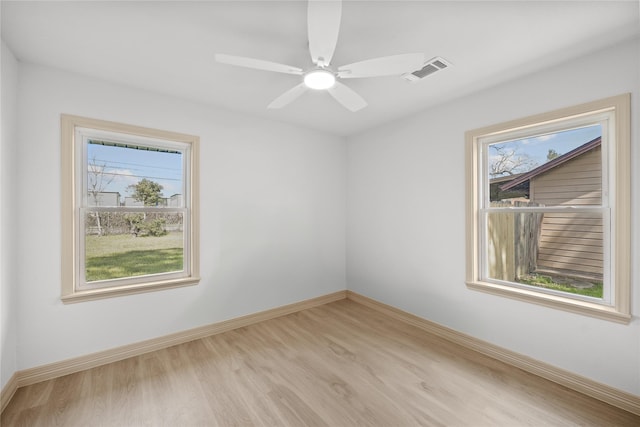 empty room featuring ceiling fan, wood finished floors, visible vents, and baseboards