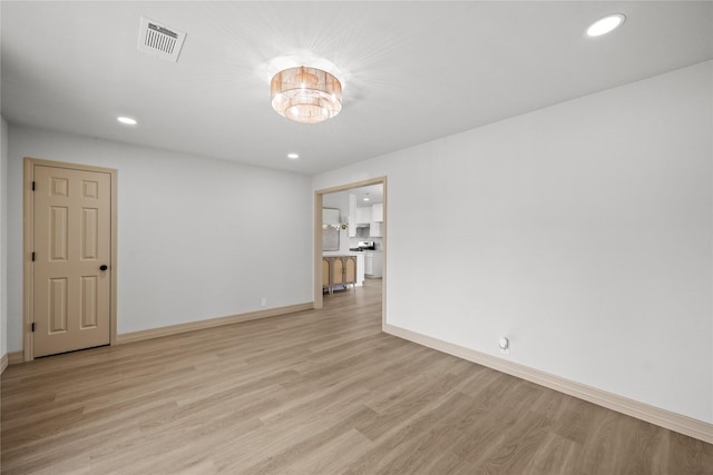 empty room featuring light wood finished floors, visible vents, recessed lighting, and baseboards