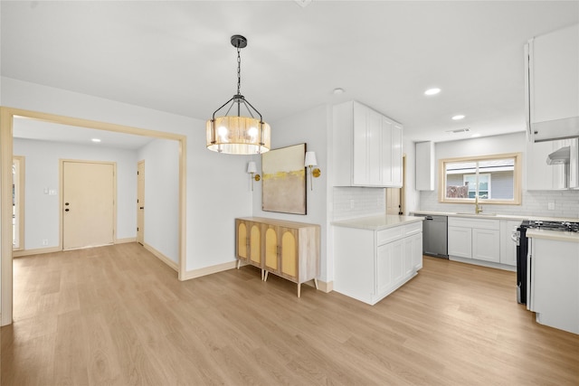 kitchen with light wood finished floors, tasteful backsplash, light countertops, appliances with stainless steel finishes, and white cabinets