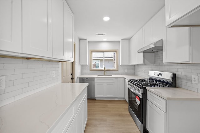 kitchen with visible vents, a sink, under cabinet range hood, appliances with stainless steel finishes, and white cabinetry