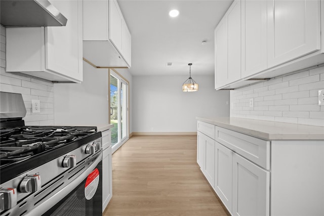 kitchen with under cabinet range hood, stainless steel range with gas stovetop, white cabinets, and light wood-type flooring