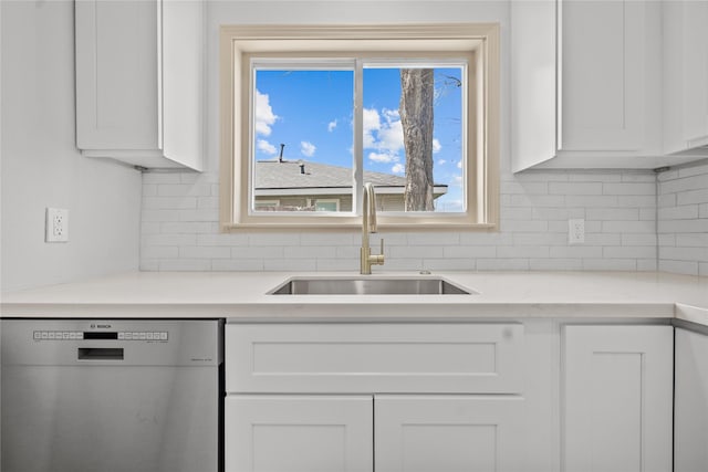 kitchen with tasteful backsplash, light countertops, stainless steel dishwasher, white cabinetry, and a sink