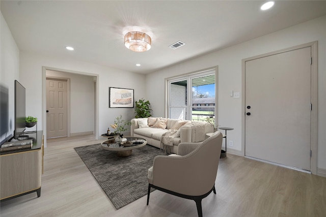 living room with light wood-type flooring, visible vents, baseboards, and recessed lighting