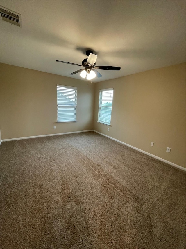 carpeted spare room with a ceiling fan, visible vents, and baseboards