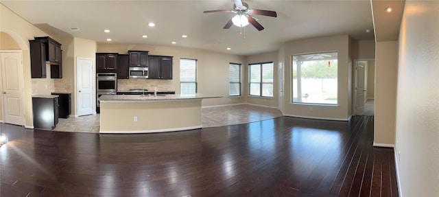 kitchen featuring open floor plan, appliances with stainless steel finishes, light wood-type flooring, and decorative backsplash