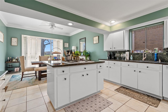 kitchen featuring white gas stovetop, light tile patterned floors, a kitchen island, backsplash, and a sink