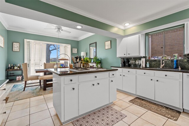 2526 Country Club Blvd, Sugar Land, TX 77478 - kitchen with a sink, a kitchen island, light tile patterned floors, white cabinets, and ornamental molding