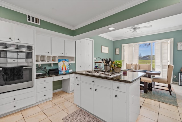 kitchen featuring gas stovetop, light tile patterned floors, double oven, ornamental molding, and white cabinetry