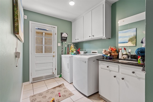 washroom with cabinet space, light tile patterned floors, baseboards, washing machine and dryer, and a sink