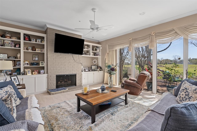 living room with ceiling fan, a brick fireplace, built in features, and crown molding