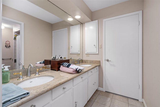 bathroom featuring double vanity, baseboards, a sink, and tile patterned floors