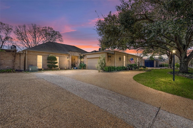 view of front of home featuring driveway, a garage, a front lawn, central AC, and brick siding