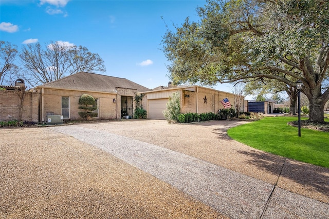 view of front of home featuring a garage, driveway, brick siding, and a front yard