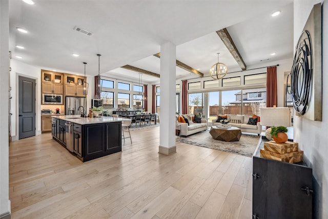 kitchen with visible vents, light wood-style flooring, open floor plan, stainless steel appliances, and light countertops