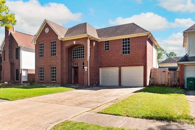 traditional-style home with driveway, fence, a front yard, a garage, and brick siding