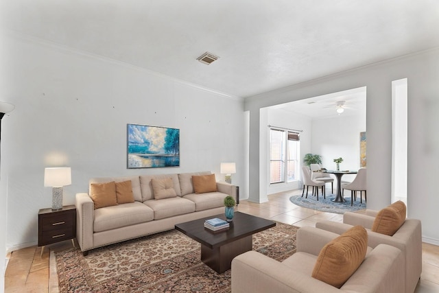 living area featuring light tile patterned floors, visible vents, crown molding, and baseboards