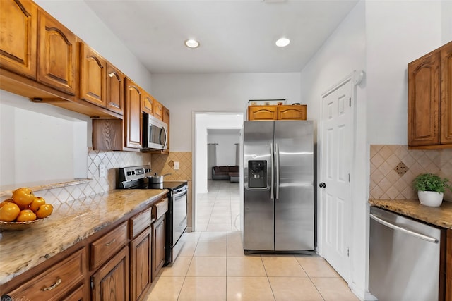 kitchen featuring light tile patterned floors, brown cabinets, stainless steel appliances, and backsplash