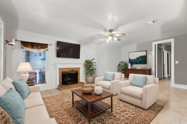 living area with light tile patterned floors, a ceiling fan, visible vents, baseboards, and a fireplace with raised hearth