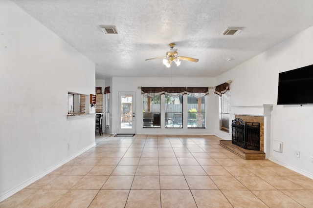 unfurnished living room featuring light tile patterned floors, a fireplace with raised hearth, visible vents, and ceiling fan