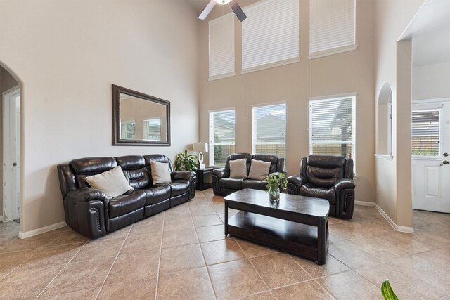 living room with a high ceiling, light tile patterned flooring, baseboards, and arched walkways