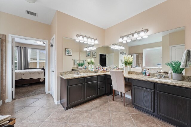 ensuite bathroom featuring vanity, tile patterned floors, visible vents, and connected bathroom