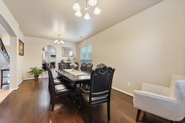 dining room featuring a chandelier, dark wood finished floors, arched walkways, and baseboards