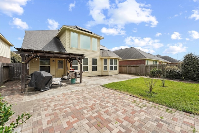 back of house featuring roof mounted solar panels, a fenced backyard, a yard, a patio area, and a pergola