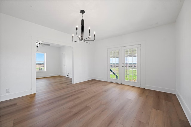 unfurnished dining area featuring a notable chandelier, french doors, baseboards, and wood finished floors