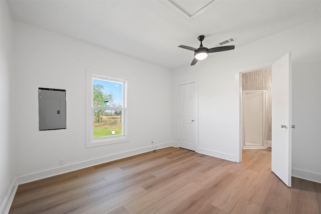 unfurnished bedroom with visible vents, light wood-type flooring, electric panel, baseboards, and ceiling fan