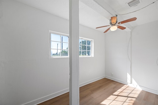 unfurnished room featuring ceiling fan, visible vents, baseboards, and wood finished floors