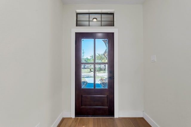 doorway featuring baseboards and wood finished floors