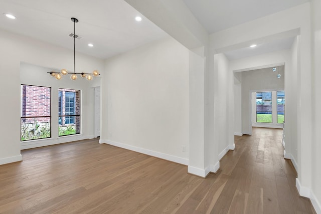 empty room with baseboards, visible vents, wood finished floors, a chandelier, and recessed lighting