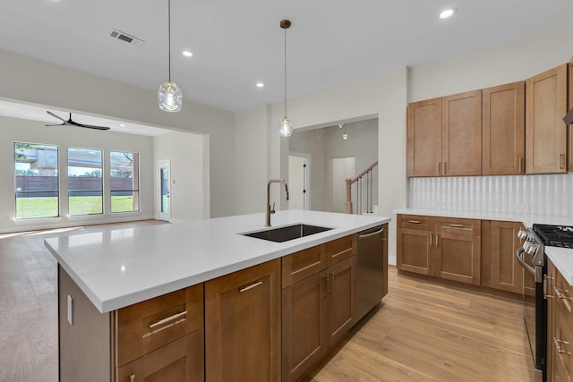 kitchen featuring stainless steel appliances, a sink, visible vents, light countertops, and light wood finished floors