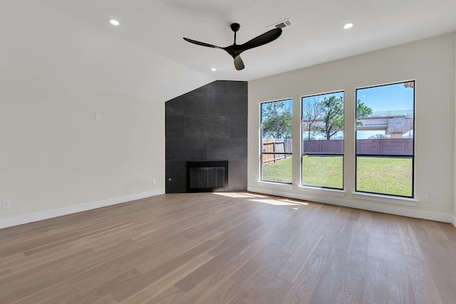 unfurnished living room with a large fireplace, vaulted ceiling, light wood-type flooring, and baseboards