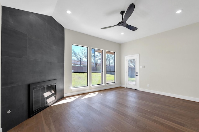 unfurnished living room featuring baseboards, a ceiling fan, dark wood-style flooring, heating unit, and a fireplace